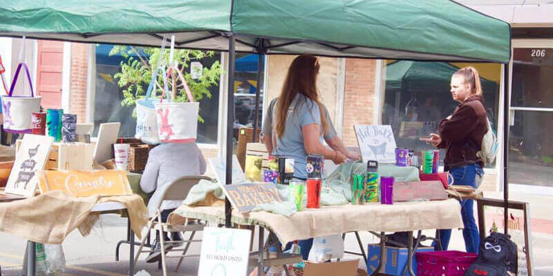 A vendor selling paintings and crafts at Art and Stroll