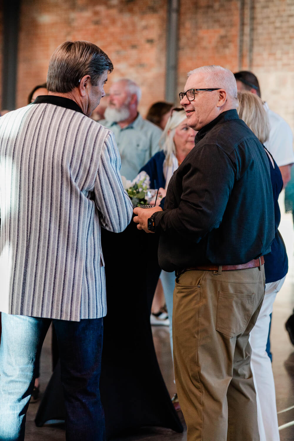 Two men talking with other guests at Plates on Pruett.