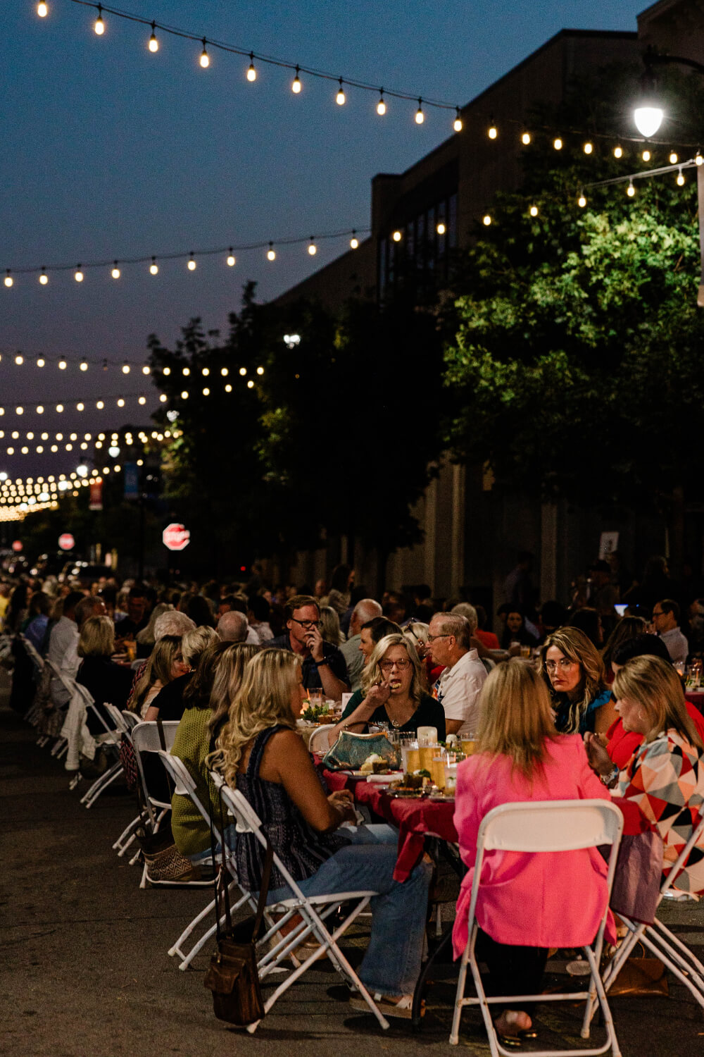 Guests enjoying dinner at tables along Pruett Street beneath the string lights.