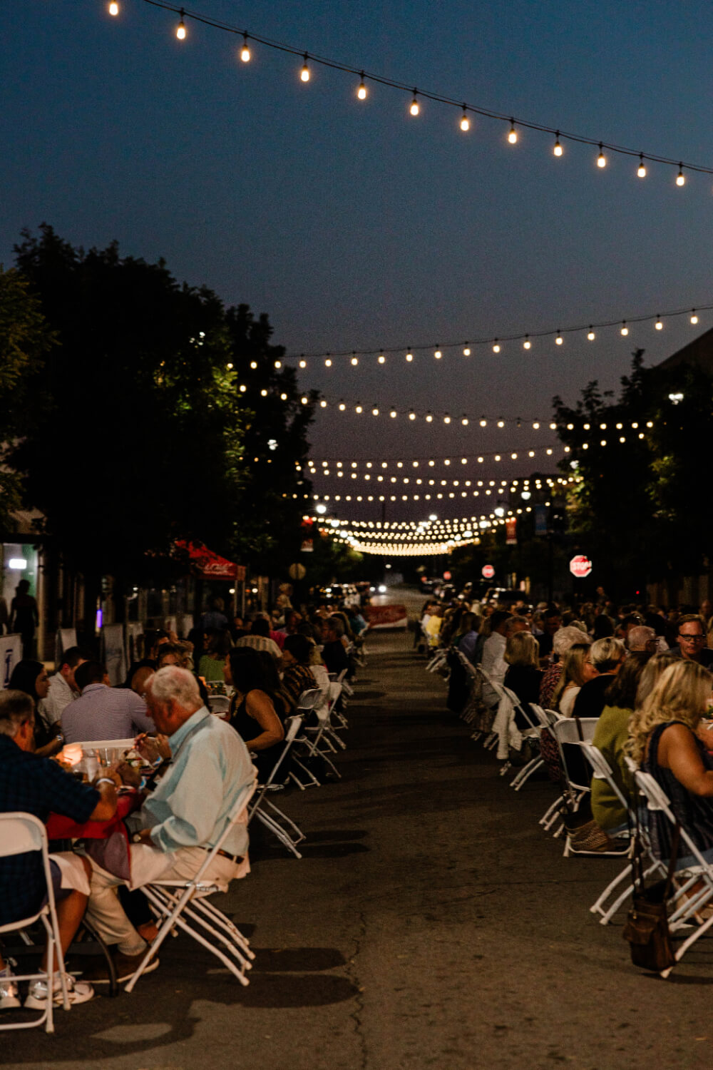Guests dining along both sides of Pruett Street beneath rows of string lights.